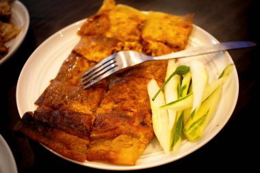 Martabak, Egg Martabak veya Egg Martabak. Yumurta, et ve baharatla doldurulmuş tuzlu hamur işleri. Martabak Telur tipik bir Endonezya sokak abur cuburudur. Tahta bir masada beyaz bir tabakta servis edildi..