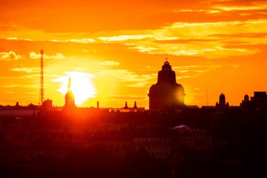 Closeup view of the sun setting down with a silhouette of buildings before it.