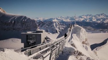 Güneşli bir kış gününde Sex Rouge 'daki Peak Walk köprüsünde yürüyen adam. Aralık 2021 'de Buzul 3000
