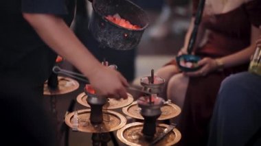 Nargile ile ile yanmış közleri yeni kömürlere dönüştürme süreci. Nargile barında küçük bir şirkette sigara içmek.