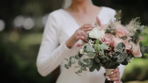 一位身穿白衣的年轻新娘轻轻地触摸着结婚花束的花瓣 Steadicam特写镜头 户外拍摄 — 图库视频影像