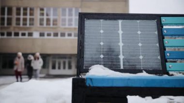 Kışın sokağın ortasında güneş paneli olan bankta. Yenilenebilir enerji, yeşil enerji bankası