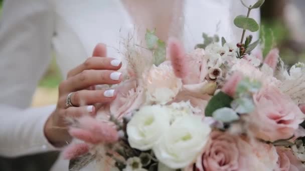 Gros plan d'une mariée tenant des fleurs dans le jardin. Charmante femme touchant les feuilles et les fleurs à l'extérieur