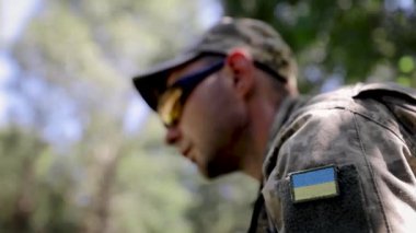 Ukrayna ordusunun askeri. Sembol sarı-mavi bayrak yakın plan. Askeri üniformalı bir adamın omzu, piksel. Ukrayna 'nın savunucusu. Yavaş çekim
