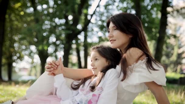 娘と母親は公園の草の上に座っている 母性と幸せな子供時代の概念 — ストック動画