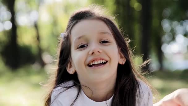 ミルクの歯を持つ6 6歳の美しい少女 彼女は公園で口を開いて笑っている 女の子の笑顔のクローズアップ — ストック動画