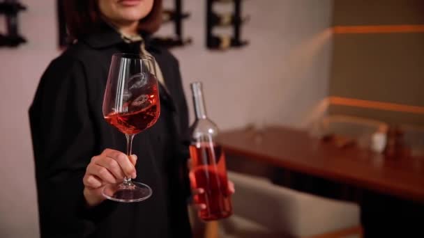 ワインセラーで赤ワインを試飲する女性の近く ハッピーな若い女性は プライベートワイナリーでワインを選んで購入します ワイングラスとボトルを保持する女性ソムリエ — ストック動画