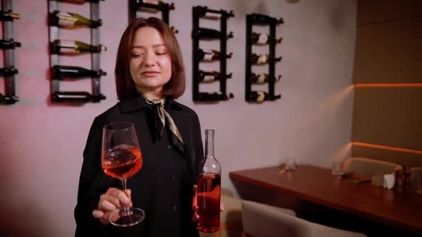 ワインセラーで赤ワインを試飲する美しい若い女性 ハッピーな若い女性は プライベートワイナリーでワインを選んで購入します ワイングラスとボトルを保持する女性ソムリエ — ストック動画