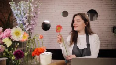 Çiçekçide kadın çiçekçinin ellerinde turuncu gerbera. Kadın bir çiçek tutuyor. Çiçekler mağaza konsepti