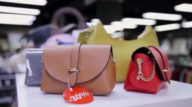 İndirim masasında sergilenen çeşitli moda el çantaları, yüzde 30 'luk satışa işaret ediyor. Çeşitli Şık Çantalar Modern Perakende Mağazasında Satışta