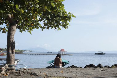 Denizde sırt çantalı bir kadın oturuyor.