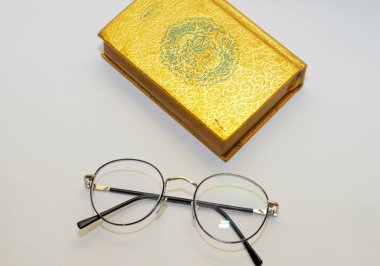 Işık arkaplanı üzerine gözlük ve kitap.