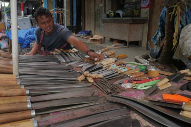 Önlüklü erkek işçi atölyede çanta taşıyor.