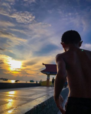 Plajda duran siyah elbiseli genç adam. 