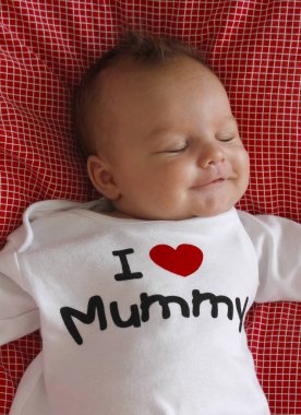 2-month old Caucasian baby boy sleeping in a red checkered duvet wearing a white T-shirt with an inscription 