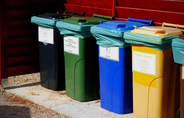 Five colorful recycle plastic bins with description in wooden shelter on the street of Croatia. Caring about environment, separating garbage into different containers. Recycling garbage concept.
