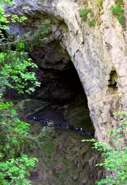 A group of tourists at the bottom of Macocha, the deepest chasm in the Czech Republic. View of the bottom of the Macocha Abyss from the top viewpoint. clipart