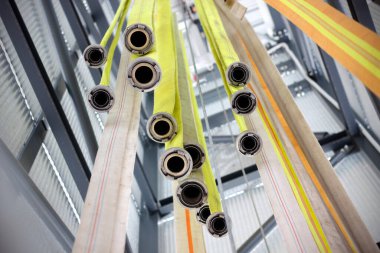 Çek gönüllü itfaiyecilerin itfaiye istasyonunun kulesinde asılı duran sarı yangın hortumlarının altında. İtfaiye ekipmanları, seçici odaklanma.