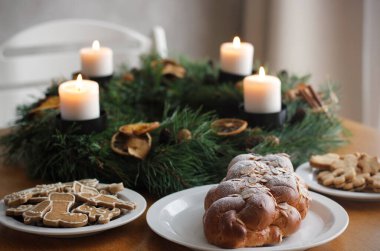 Traditional Czech and Slovak Christmas sweet plaited bread called vanocka (in Slovak vianocka), Christmas cookies and a Christmas advent wreath with four burning candles on wooden table. clipart