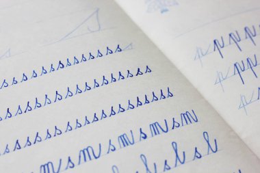 Not defterindeki bir çocuk tarafından el yazısıyla yazılmış mavi harflerin yakın çekimi. Okul eğitimi ve el yazısıyla yazılmış belgeler. El yazısıyla eski okul yazıları. Okul konseptine dönelim..