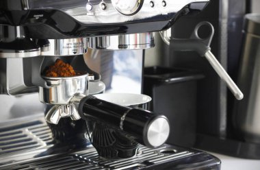 Kahve makinesinde yapılan espresso işleminin bir parçası olarak portafilterdeki taze kahve çekirdeklerini yakın plan çekiyoruz. Evdeki espresso makinesinde kahve yapıyorum..