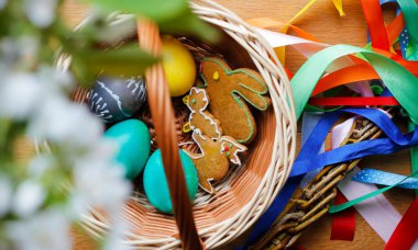 Paskalya yumurtası, zencefilli kurabiye ve renkli kurdeleli Paskalya kırbacıyla dolu sepetin üst görüntüsü. Çek ve Slovak Paskalyası