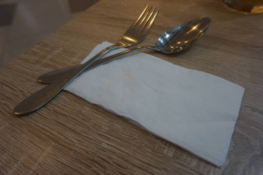 Fork with spoon and tissue paper on a wooden table in a cafe.
