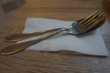 Fork with spoon and tissue paper on a wooden table in a cafe.