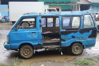 Indonesian public transportation, old and damaged blue angkot, parked on the side of the main road