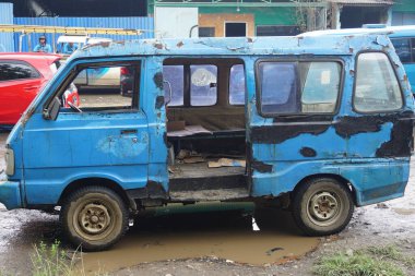Indonesian public transportation, old and damaged blue angkot, parked on the side of the main road