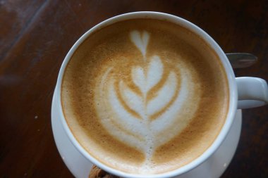 Tahta masadaki bir fincan sıcak sütlü kahveyi kapat. Latte espresso ve buğulanmış sütle yapılan bir kahve içeceğidir..