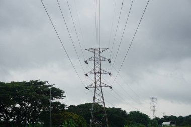 Yüksek voltajlı elektrik dağıtım direği, gün batımında ağaçların gölgesi, enerji üreticisi teknoloji endüstrisi için elektrik dağıtım pilonu hattı