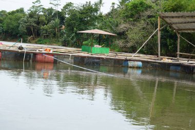 Gölün ortasında bir balık çiftliği, çok basit görünüyor, bambudan yapılmış ve tel bir çit bariyer.