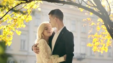 Düğün gününde gelin ve damadın portresi Sonbahar parkında duruyor ve sarılıyor