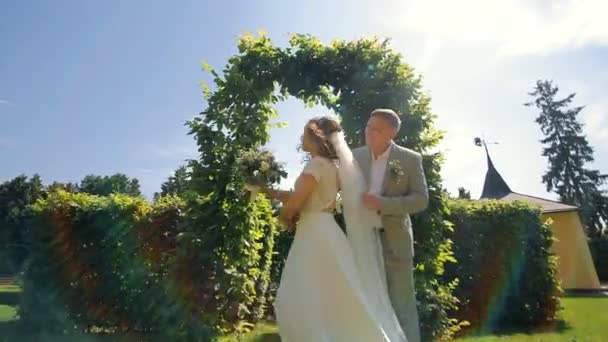新婚夫妇在一个绿色拱门附近跳舞 新娘绕着新郎转 新婚夫妇的婚舞 — 图库视频影像