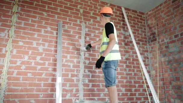 男がレンガの壁を耕している 経験豊富な職人がレンガの壁を耕す — ストック動画
