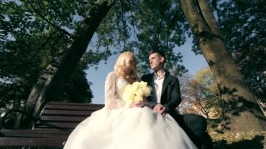 Parktaki bir bankta, damat ve gelin birlikte oturuyorlar. Autumn Park 'ta güzel bir sonbahar sabahı.