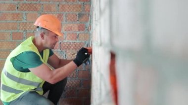 Duvarların alçısız tuğla olduğu bir odada elektrik prizleri için kutular yerleştirmek