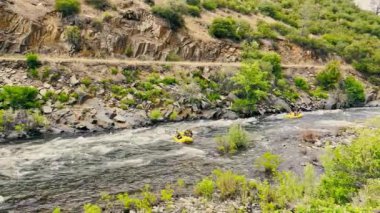 California dağlarında hızlı bir dağ nehrinde rafting yapmak. Sarı teknelerdeki kirişler nehirde aşırı yelken açıyor.
