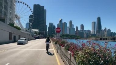 Chicago, Illinois, ABD - 05.10.2022 Lakefront Trail 'de kalabalıklar arasında bisiklet sürmek. Güneşli bir günde Michigan rıhtımında bisiklet sürmek.