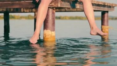 Mens feet in the lake. A man sitting on a bridge with his legs dangling in the water