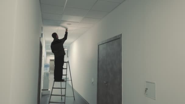 Master Electrician Standing Ladder Changing Light Bulb Dark Corridor — 비디오