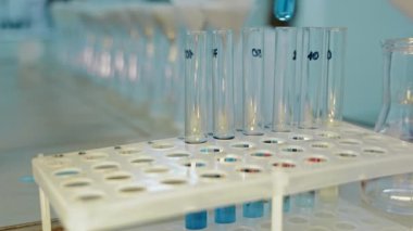 Study Of A Blue Substance In A Test Tube. A Scientist In A Laboratory Puts A Cork In A Tripod With A Blue Substance For Research