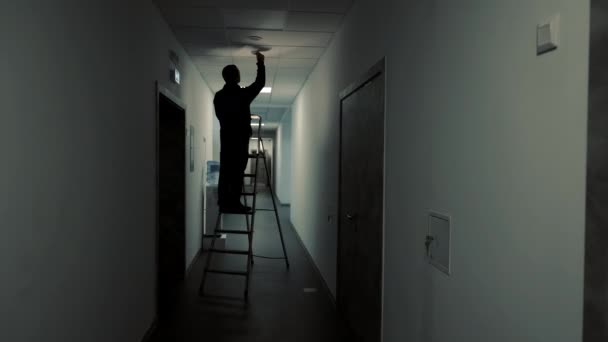 Silhouette Master Electrician Standing Ladder Changing Light Bulb Dark Corridor — Wideo stockowe