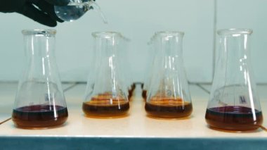 Kimyasalların mataralarda karıştığı bilimsel araştırma laboratuvarı. Araştırmacı test tüpüne çözeltiden birkaç damla ekler.