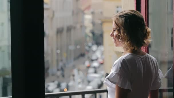 一个快乐的白人女人站在窗边 微笑着看着一束美丽的花 在窗边等着 — 图库视频影像
