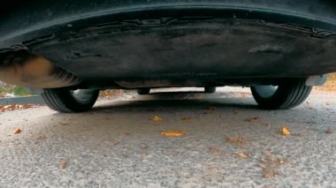 Araba, kuyu ve çukurlardan geçen zorlu bir yolda gidiyor. Off-road seyahati kavramı. Kamera arabanın altına yerleştirilir ve sürerken lastiklerin ve süspansiyonun görüntüsünü gösterir.