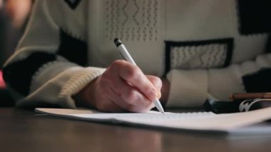 Bir kadın konferans sırasında kalemle not alır, yakın plan.