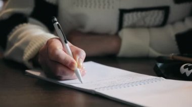 Bir kadın konferans sırasında kalemle not alır, yakın plan.