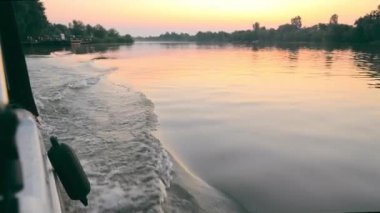 Gün batımında motorlu bir teknenin görüntüsü. Küçük bir nehrin ağzında hızlı hareket eden bir tekne. Motorlu tekneyle git.